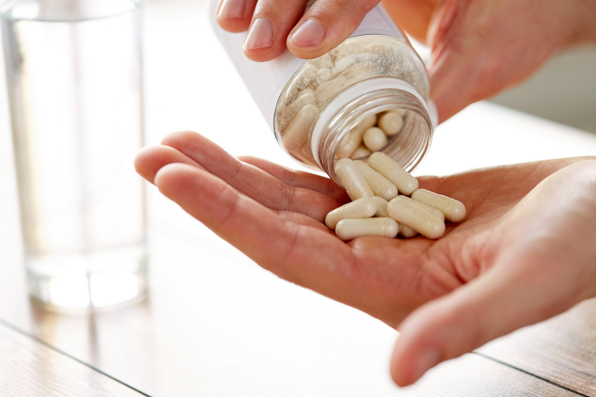 close-up-of-man-pouring-pills-from-jar-to-hand-PUGULFB.jpg